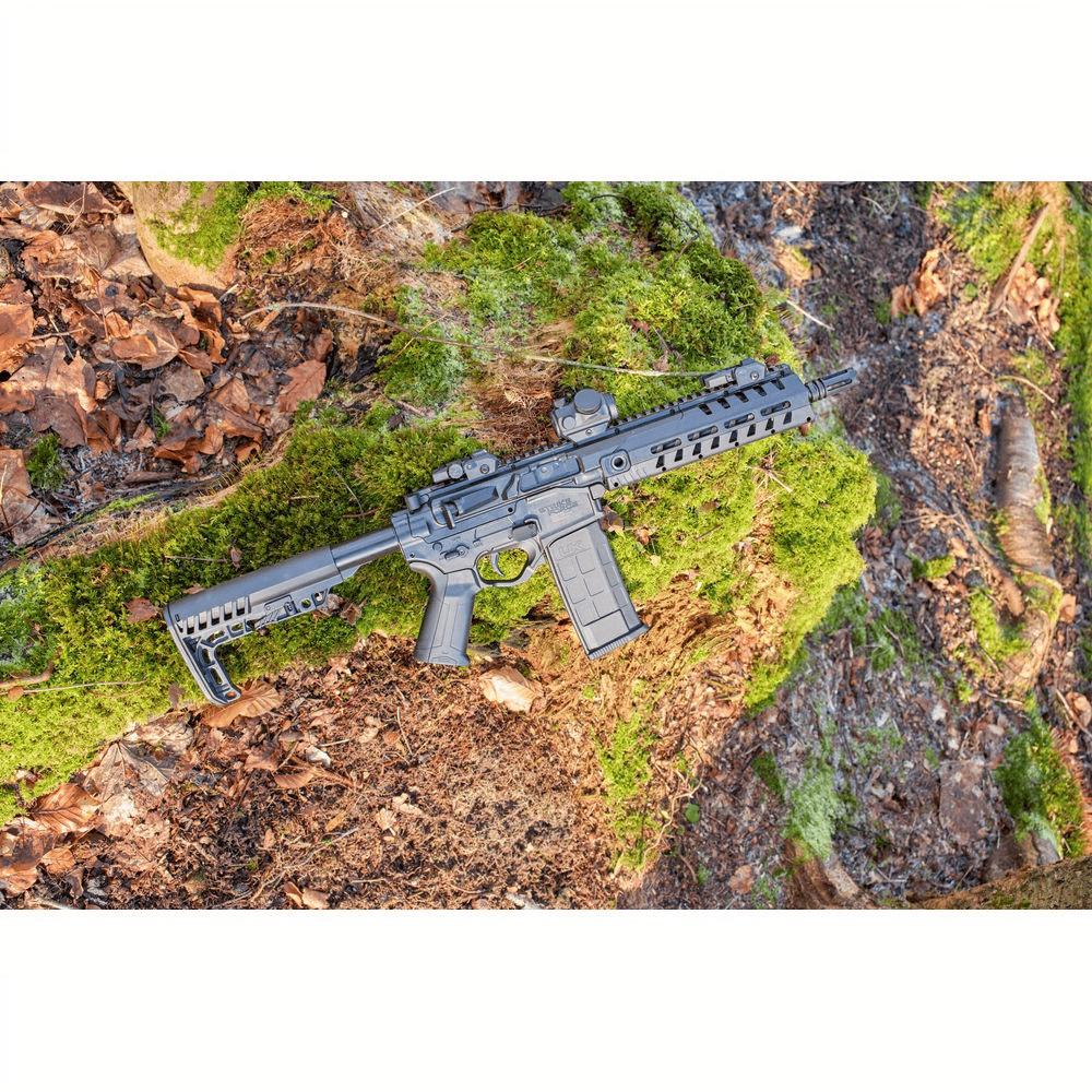 id-paintball UX Strike Force CO2-Sportgewehr im AR-Design mit M-LOK-Vorderschaft auf einem moosbewachsenen Baumstamm