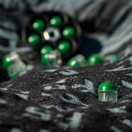 id-paintball First Strike FSR cal. 50 Munition mit durchsichtiger Schale und grüner Füllung auf dunklem Stoff