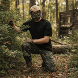 id-paintball US T-Shirt in Schwarz mit Ärmeltaschen aus Baumwolle, getragen von einem Paintballspieler im Wald