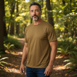 Ein Mann trägt ein atmungsaktives id-paintball Tactical T-Shirt in Coyote Tan in einer Waldumgebung.