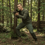 id-paintball US Langarmshirt in Oliv mit Ärmeltaschen aus Baumwolle, getragen von einem Mann im Wald beim Training
